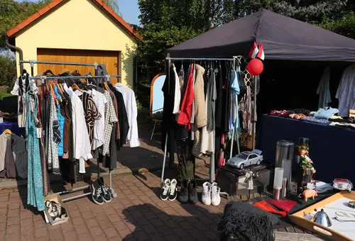 Kleiderstangen mit Second-Hand-Kleidung vor Garage 