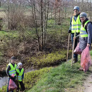 Zwei Kinder sind ins Bachbett hinabgestiegen. während die Eltern oben am Weg beobachten.
