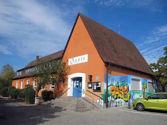 Blick auf das Jugendhaus mit Spitzdach und einem davor parkenden Auto.