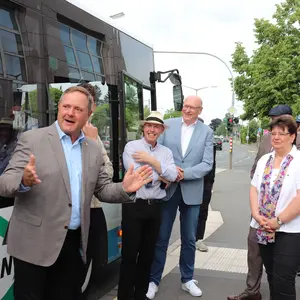 Mehrere Personen vor einem Bus. Der Landrat spricht und gestikuliert.