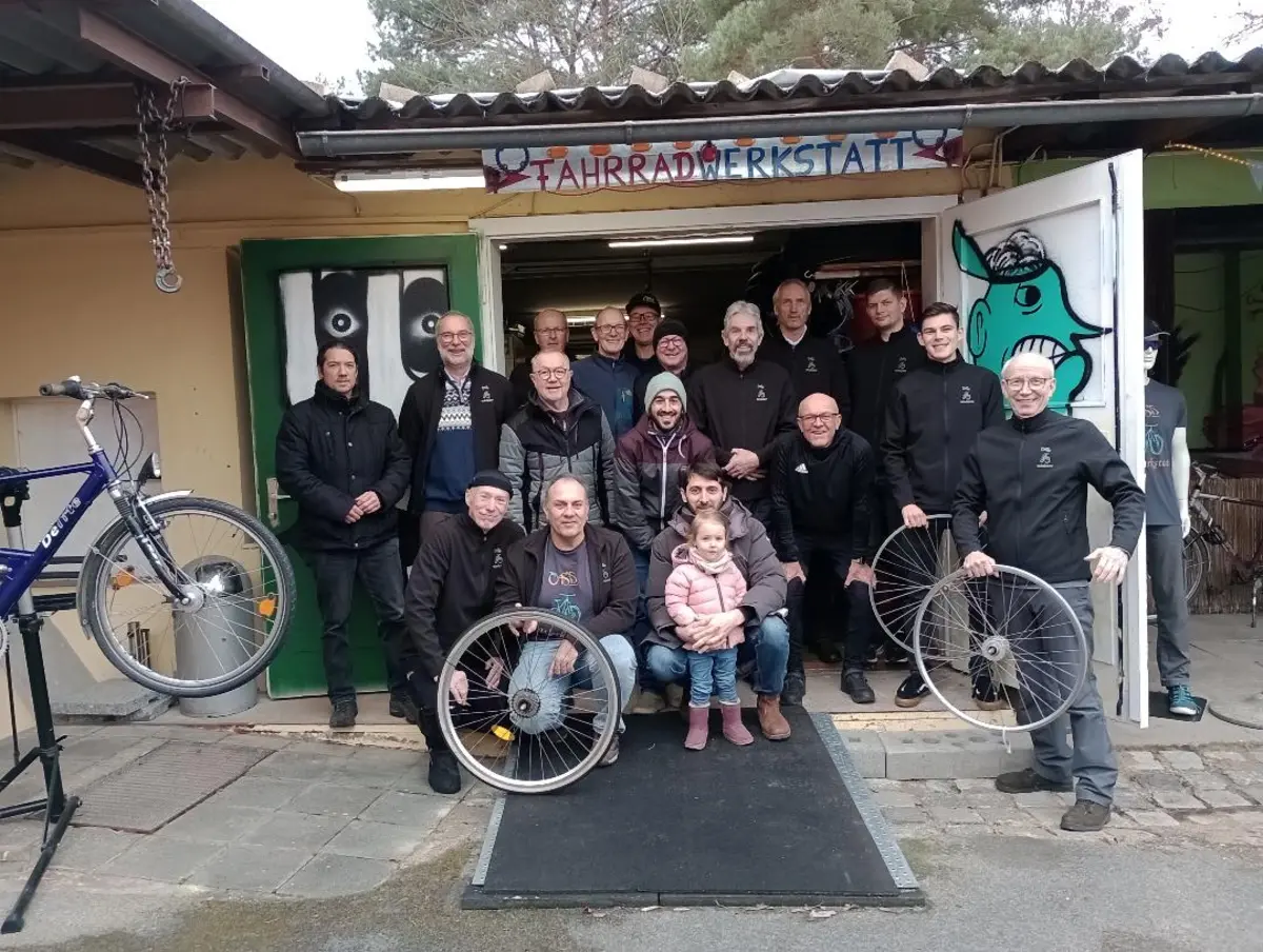 Gruppenfoto mit Rad vor der Werkstatttür