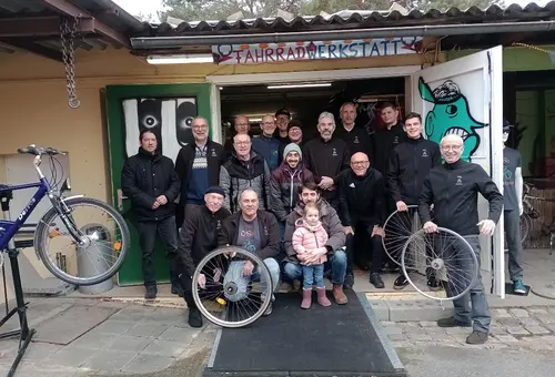 Gruppenfoto mit Rad vor der Werkstatttür