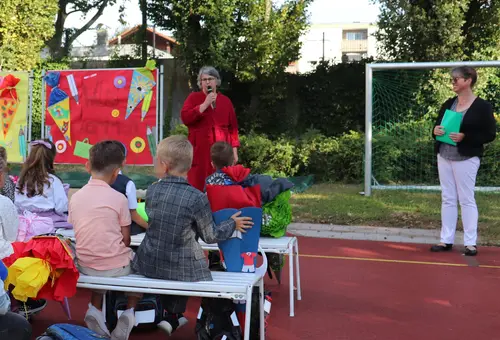 Birgit Huber im roten Bademantel und Gabriele Eitel vor den Erstklässlern.