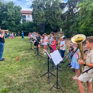 Ein Dirigent (links im Bild) vor rinr Bläserklasse, die aus Schulkindern besteht.