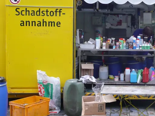 Container mit der Aufschrift Schadstoffannahme. Davor und darin verschiedene Gefäße. 