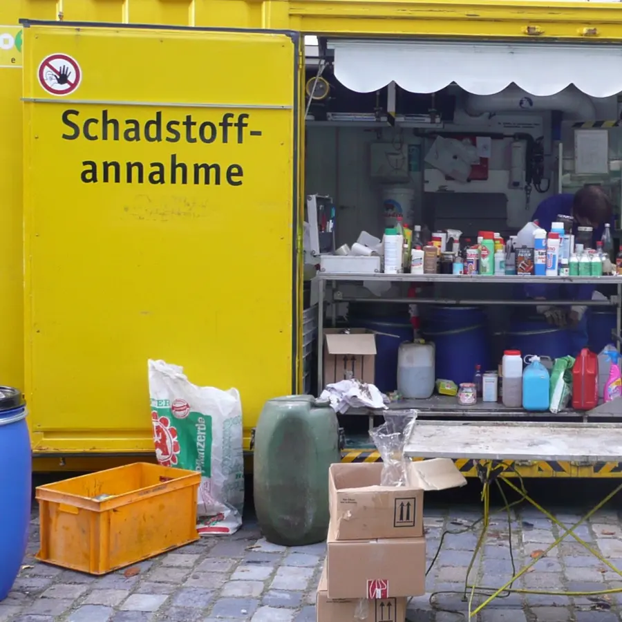 Container mit der Aufschrift Schadstoffannahme. Davor und darin verschiedene Gefäße. 