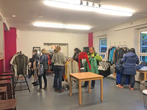 Menschen stehen vor Kleiderständern mit Tauschkleidung
