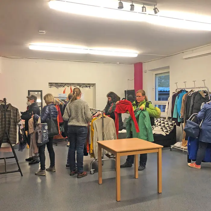 Menschen stehen vor Kleiderständern mit Tauschkleidung