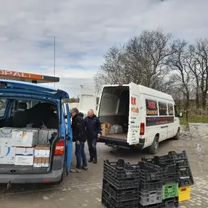 Zwei Lieferwagen, deren Waren umgeladen werden.