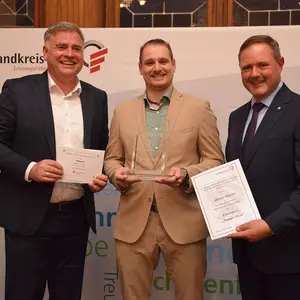 Drei Männer blicken in die Kamera