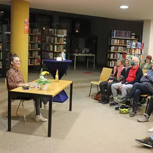 Katja Diehl sitzt link im Bild an einem Tisch. Vor ihr eine Reihe von Gästen. 