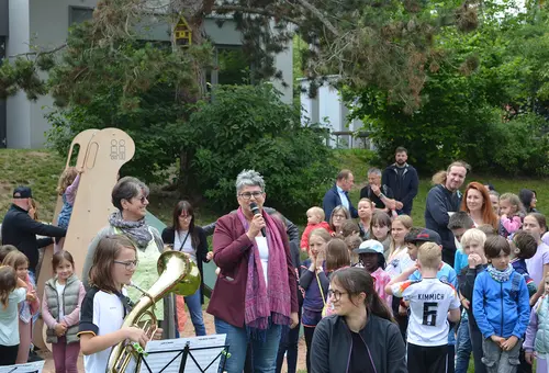 Eine Frau am Mikrofon umringt von Kindern und Erwachsenen
