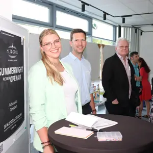 die beiden Personen an einem Stehtisch vor einer mobilen Stellwand 