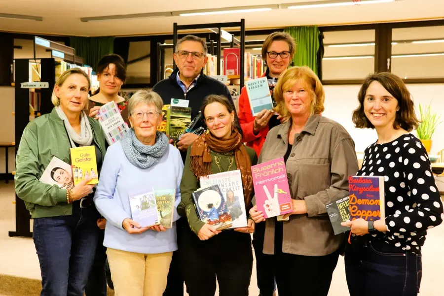 ein Mann und acht Frauen mit Büchern in den Händen 