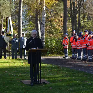 Ein Mann am Rednerpult auf der Rasenfläche vor dem Mahnmal