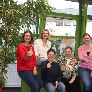 5 Frauen sitzen auf einem Sofa und recken die Daumen in die Kamera