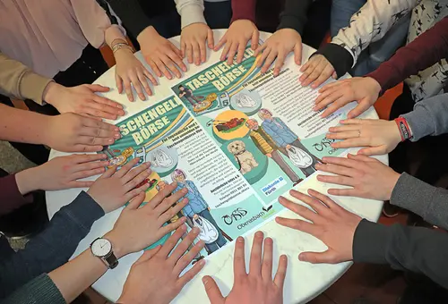 Helfende Hände im Kreis auf einem Tisch beim Handy-ABC