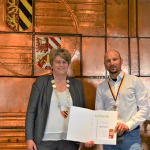 Die Bürgermeisterin überreicht dem Sportler die Urkunde