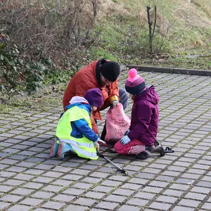 Zwei Kinder sammeln Müll vom Boden auf.