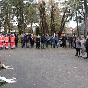 Um den Platz stehen mehrere Personen in stillem Gedenken