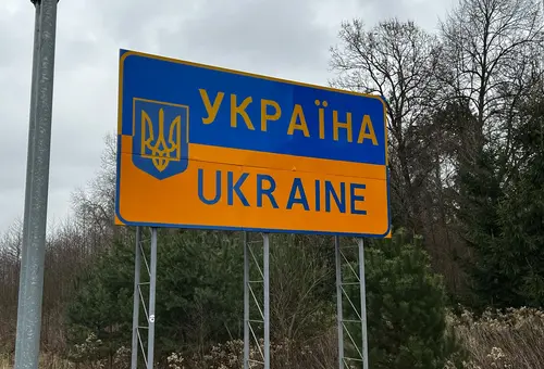Schild in Gelb und Blau mit der Aufschrift Ukraine in lateinischen und kyrillischen Buchstaben