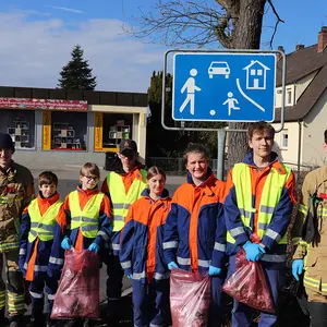 Acht Jugendliche in Feuerwehruniform mit ihren Müllsäcken.
