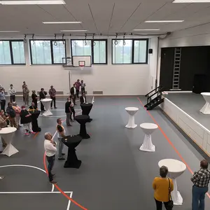 Birgit Huber spricht auf der Bühne und zahlreiche Gäste an Stehtischen hören zu.