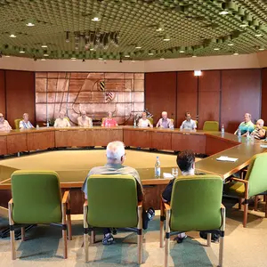 Menschen sitzen an den Tischen, die im Achteck aufgebaut sind.