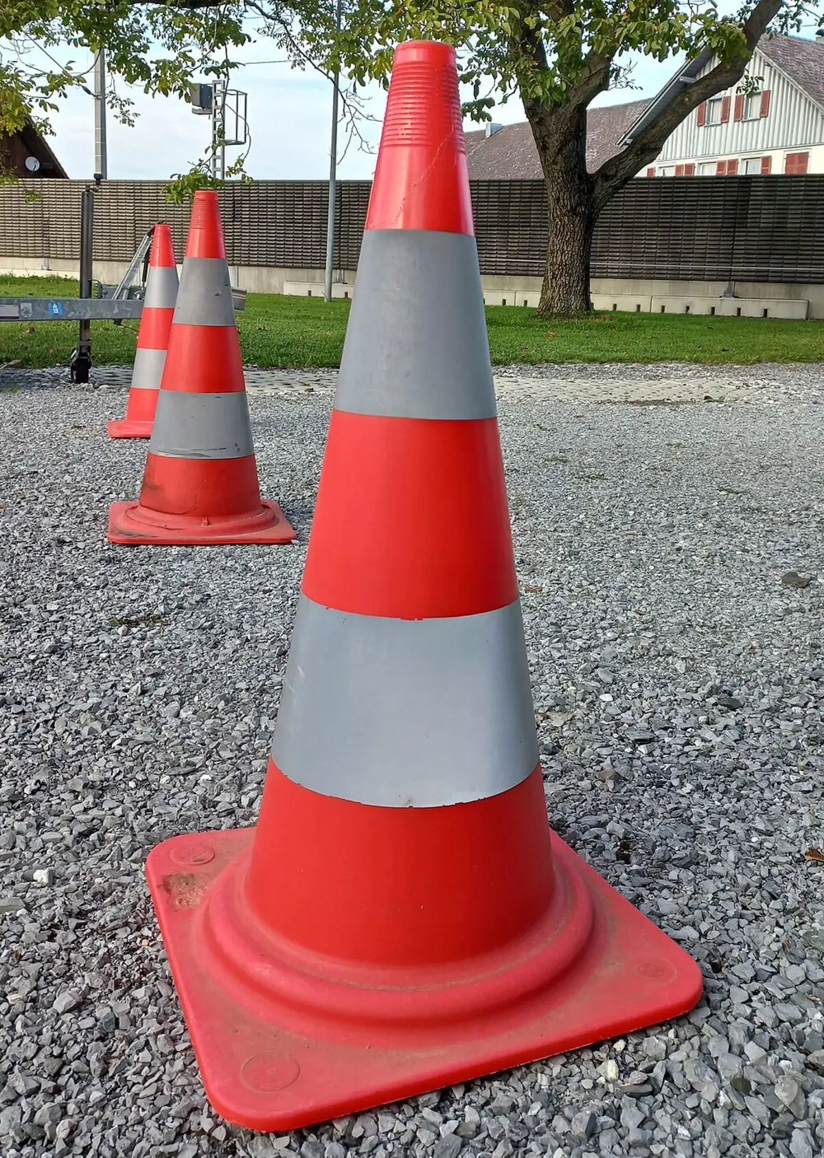 Drei rot-weiße Pylone in Nahaufnahme hintereinander auf einer Straße 