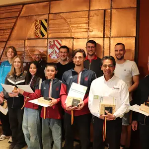 Gruppe von Menschen vor dem Stadtwappen im Sitzungssaal