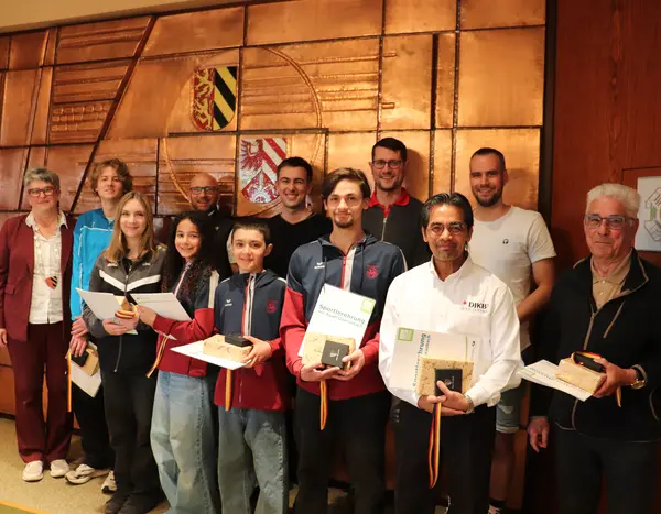 Gruppe von Menschen vor dem Stadtwappen im Sitzungssaal