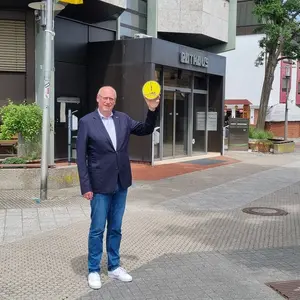 Bürgermeister im Anzug halt Uhr, die auf 5 vor 12 steht vor dem Rathauseingang