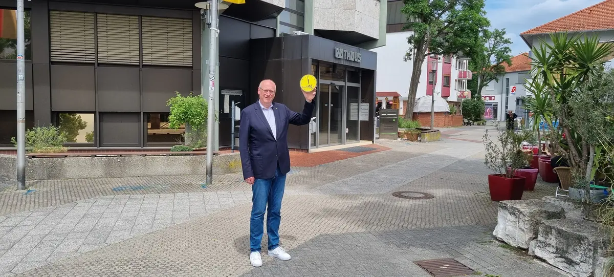 Bürgermeister im Anzug halt Uhr, die auf 5 vor 12 steht vor dem Rathauseingang
