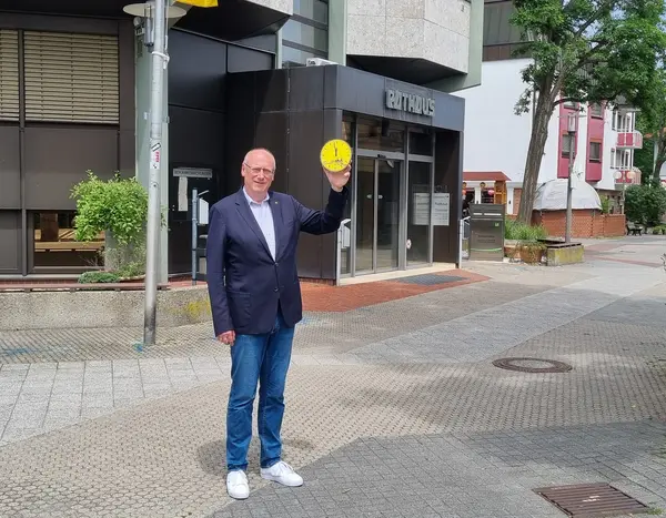 Bürgermeister im Anzug halt Uhr, die auf 5 vor 12 steht vor dem Rathauseingang