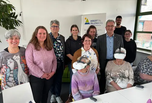 Sieben Frauen und zwei Männer beim Gruppen fot, Im Vordergrund zwei Frauen mit VR-Brille