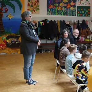 Eine Frau spricht vor den Kindern, die sich zu ihr umdrehen.