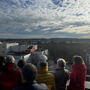 Menschen auf der Dachterrasse vor einer schönen Landschaft mittoller Wolkenformation am Himmel