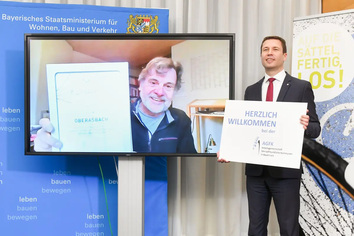 Landrat Mathias Dießl heißt die neuen Mitglieder willkommen. Auf einem Bildschirm ist Bürgermeister Norbert Schikora zu sehen.