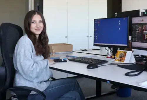 junge Frau vor Schreibtisch mit zwei Bildschirmen 