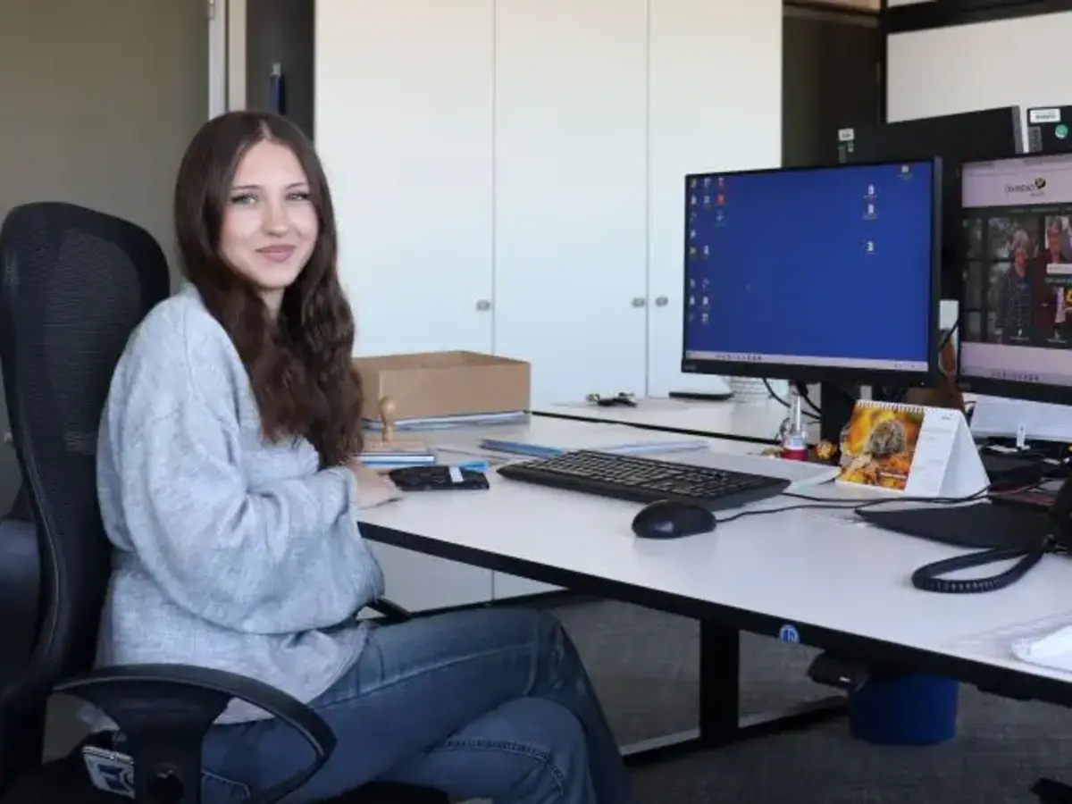 junge Frau vor Schreibtisch mit zwei Bildschirmen 