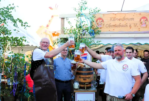 Mehrere Männer prosten sich mit erhobenen Bierkrügen zu