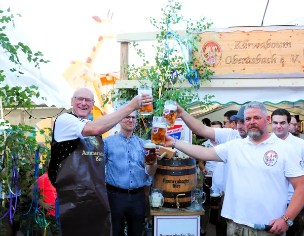 Mehrere Männer prosten sich mit erhobenen Bierkrügen zu