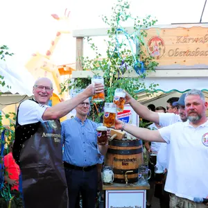 Mehrere Männer prosten sich mit erhobenen Bierkrügen zu