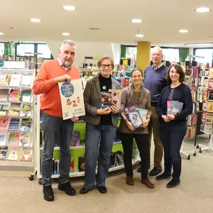 5 Personen halten Bücher und ein Plakat in den Händen 