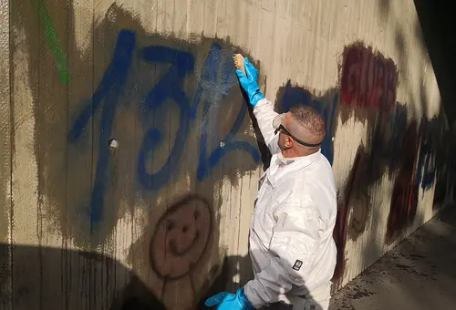 Ein Mann in Schutzkleidung reinigt mit einer Handbürste die Wand.