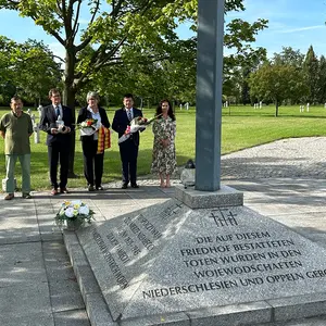 Fünf Personen im HIntergrund an einem Kriegerdenkmal (im Vordergrund)
