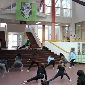 Coach mit den Schülern in der Aula beim Aufwärmen