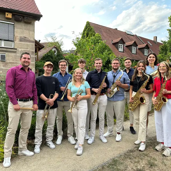 11 Musikerinnen und Musiker mit verschiedenen Blechblasinstrumenten.