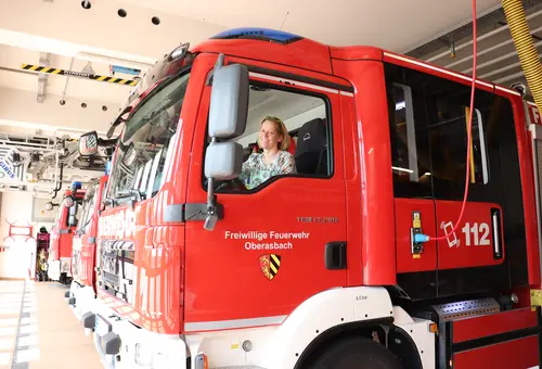 Claudia Weiß sitzt am Steuer eines Feuerwehrautos. Auf der Tür die Aufschrift Freiwillige Feuerwehr Oberasbach und das Wappen; auf der Seite die Telefonnummer 112.