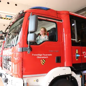 Claudia Weiß sitzt am Steuer eines Feuerwehrautos. Auf der Tür die Aufschrift Freiwillige Feuerwehr Oberasbach und das Wappen; auf der Seite die Telefonnummer 112.